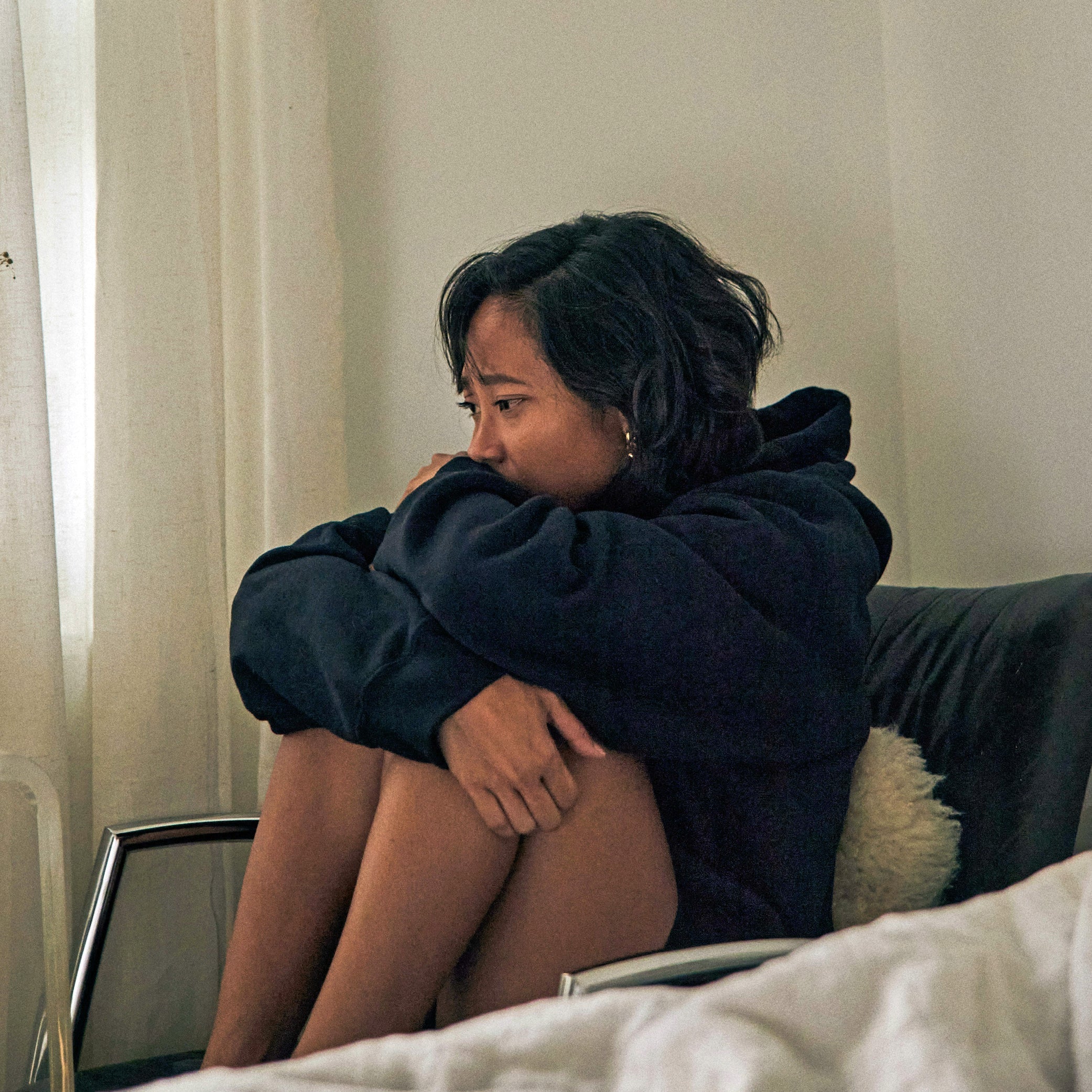 Women sitting on a black chair in a dark hoodie looking sad